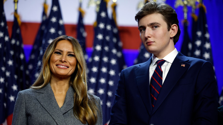 Barron and Melania Trump stand on stage with Barron in a navy suit