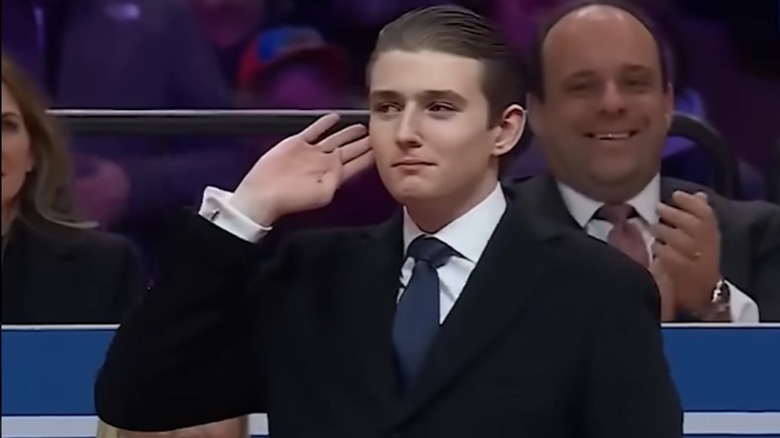 Barron Trump holding his hand up to his ear