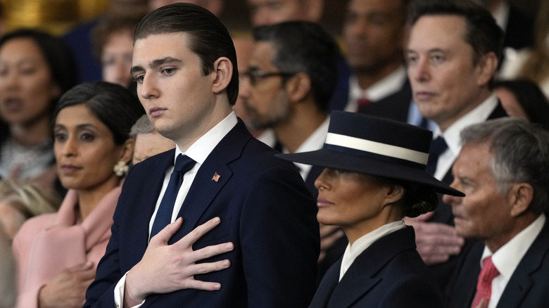Barron Trump with his hand over his heart next to Melania Trump