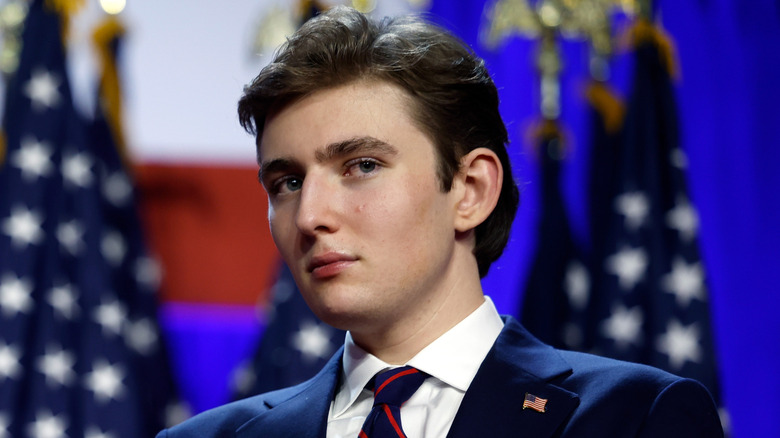 Barron Trump posing in a suit at the Palm Beach Convention Center.