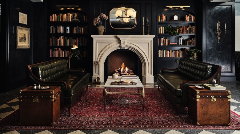 Opulent white fireplace, green leather couches, and library at Hotel 1928