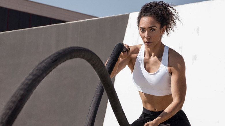 Woman concentrating with battle ropes