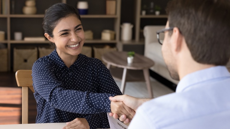 smiling woman shaking man's hand