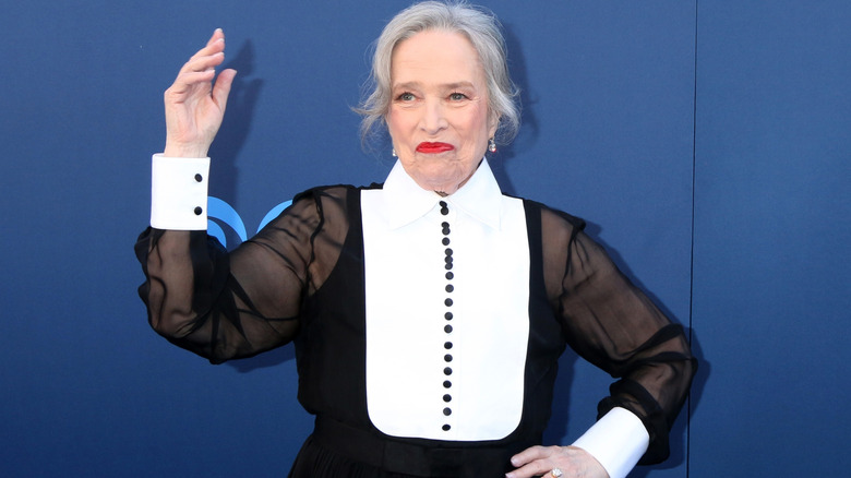 Image of Kathy Bates smiling and waving on the red carpet of an event
