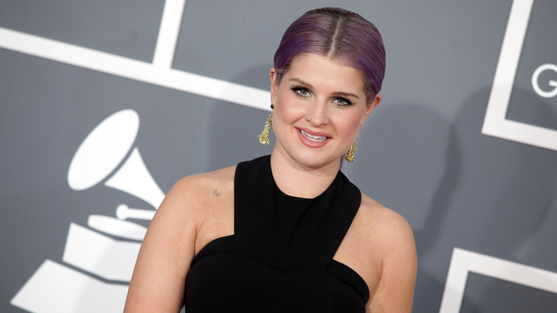 Titled photo of Kelly Osbourne with purple hair in black dress.