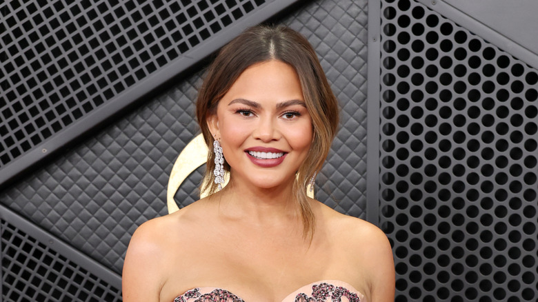Chrissy Teigen smiling on the 2026 Grammy's red carpet
