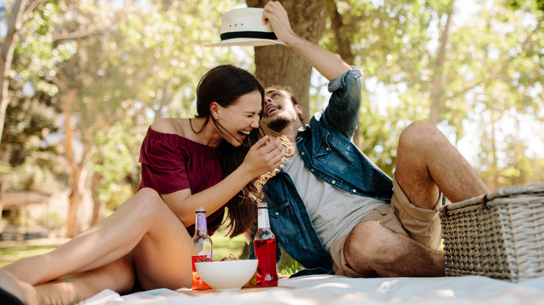 woman laughing at man playing with her hat