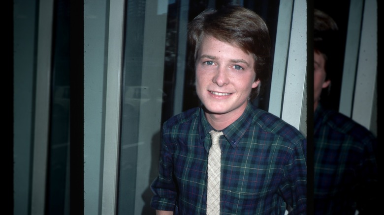 Michael J. Fox wearing a tie and plaid shirt and smiling