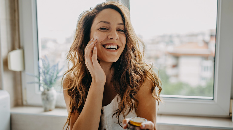 smiling woman moisturizing face