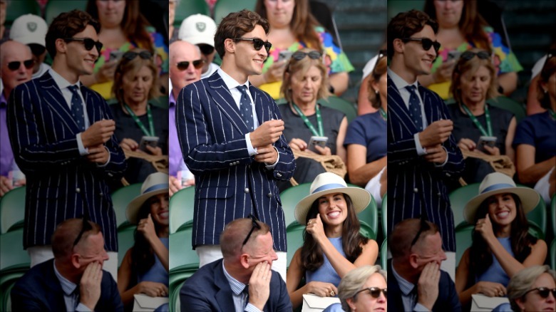 George Russell watching tennis at Wimbledon in a pinstripe suit and wearing sunglasses.