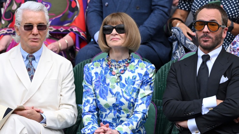 Baz Luhrmann, Anna Wintour, and Tom Ford watching the tennis at Wimbledon in the Royal Box, all wearing sunglasses