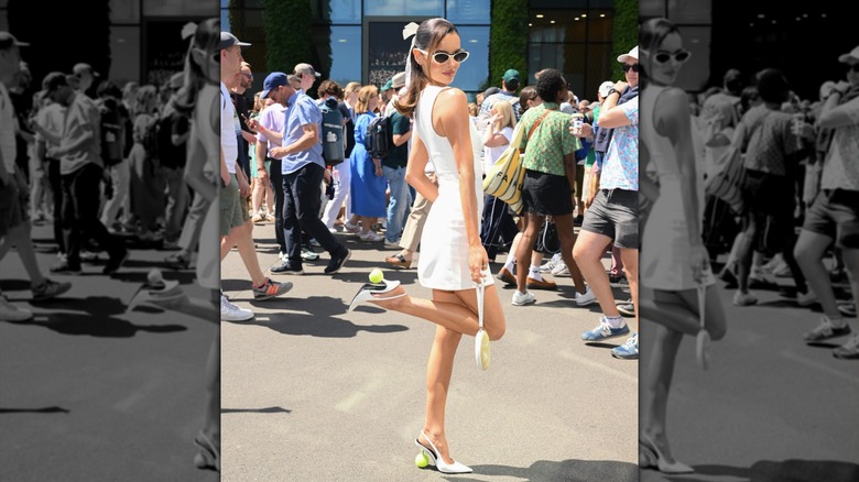 Maura Higgins kicking one leg up and wearing a white dress at Wimbledon.