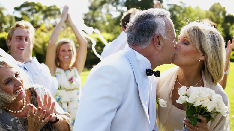 guests clap as married couple kisses outside 