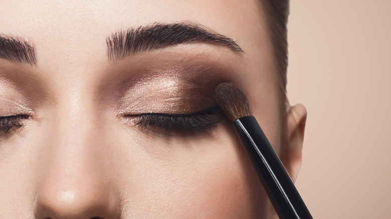 Person wearing eyeshadow with a brush