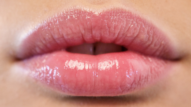Extreme close-up of woman's lips that have lip gloss on them