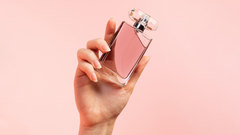 Hand holding pink perfume bottle