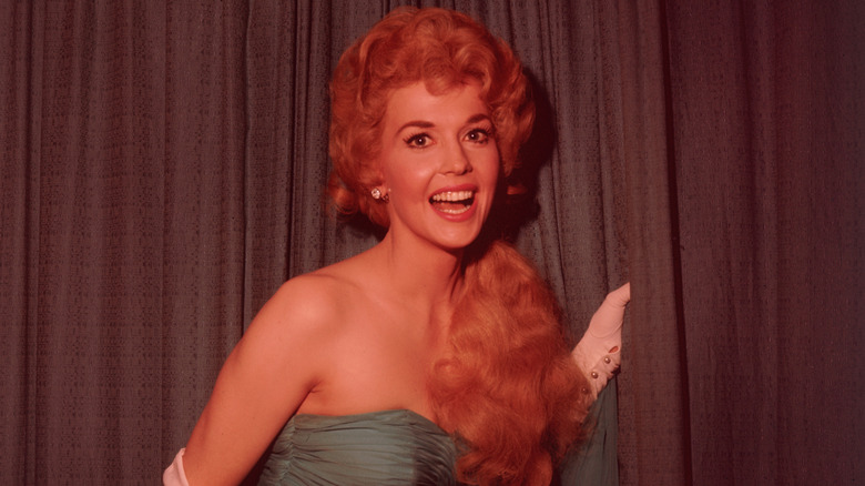 Donna Douglas smiling in front of a curtain
