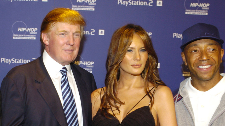 Russell Simmons posing beside Melania and Donald Trump