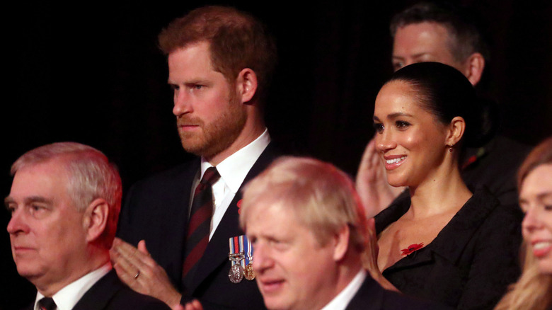 Prince Andrew, Prince Harry, and Meghan Markle clapping in audience