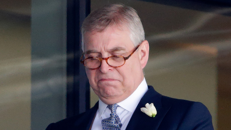 Prince Andrew wearing glasses and looking down
