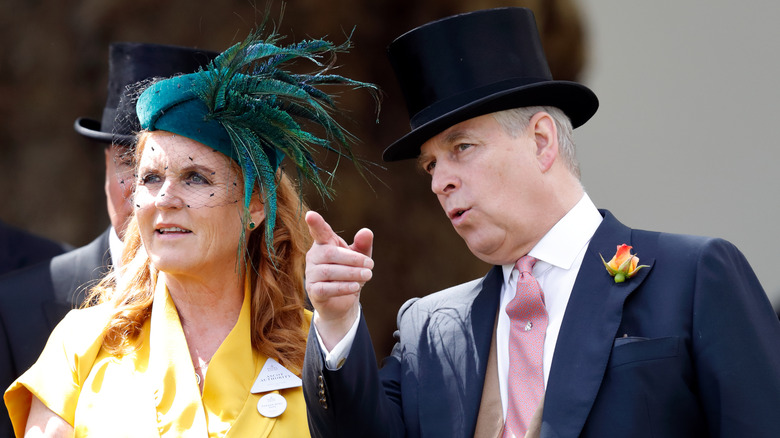 Prince Andrew pointing ahead of him while he leans in to talk to Sarah, Duchess of York