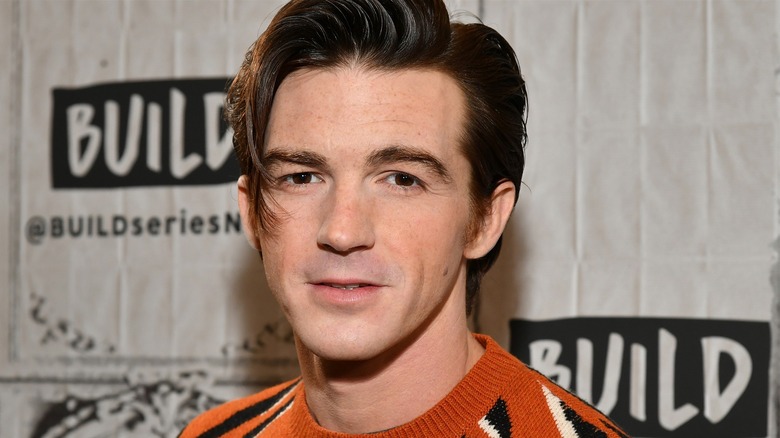 A closeup of Drake Bell on a step and repeat