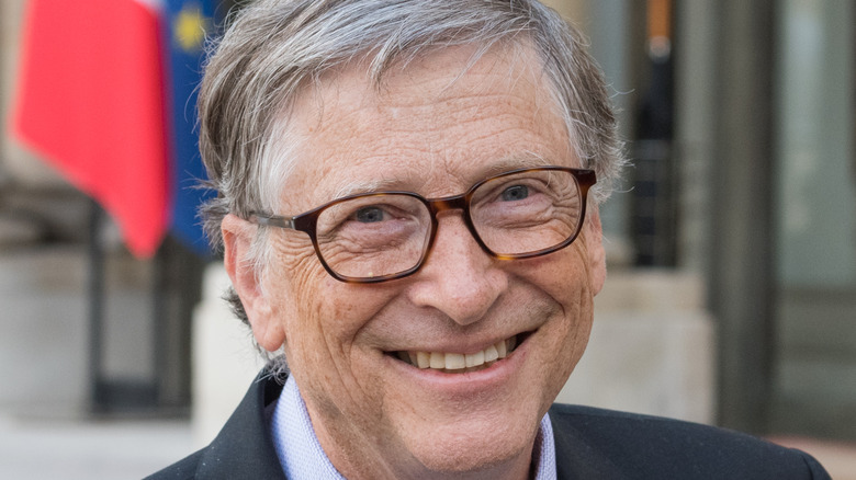 Bill Gates smiling and standing on the steps of a building
