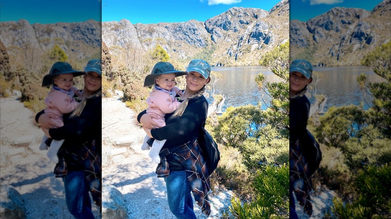Bindi holds Grace in front of a scenic background