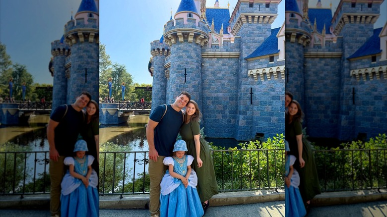 Chandler Powell, Bindi Irwin and Grace smile in front of a castle at Disney World