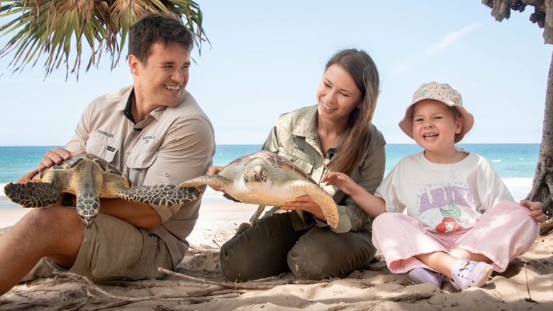 Chandler Powell and Bindi Irwin hold turtles next to daughter Grace