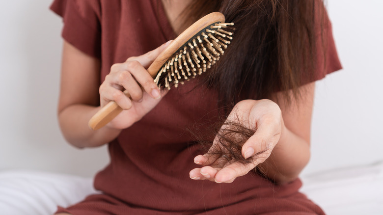 A woman pulling out clumps of hair from a brush