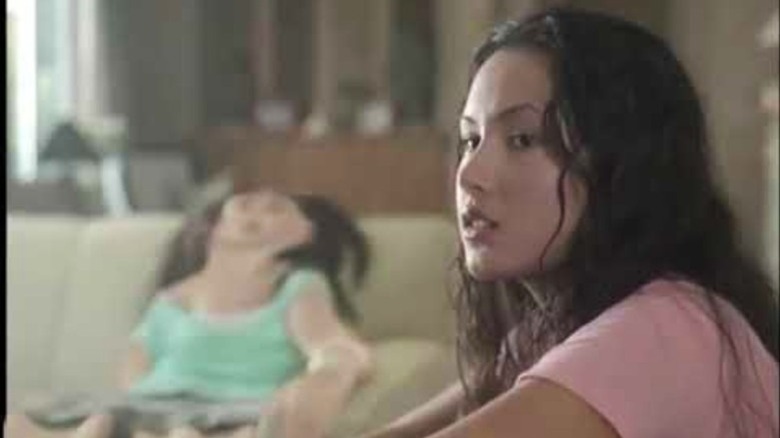 One girl looking off-screen while another melts into a couch.