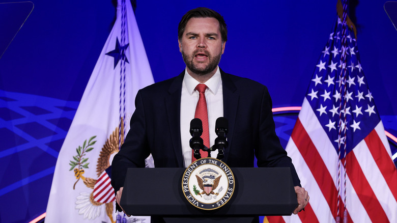 JD Vance giving a speech onstage in a black suit