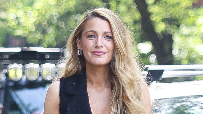 Blake Lively smiles awkwardly outdoors in front of car