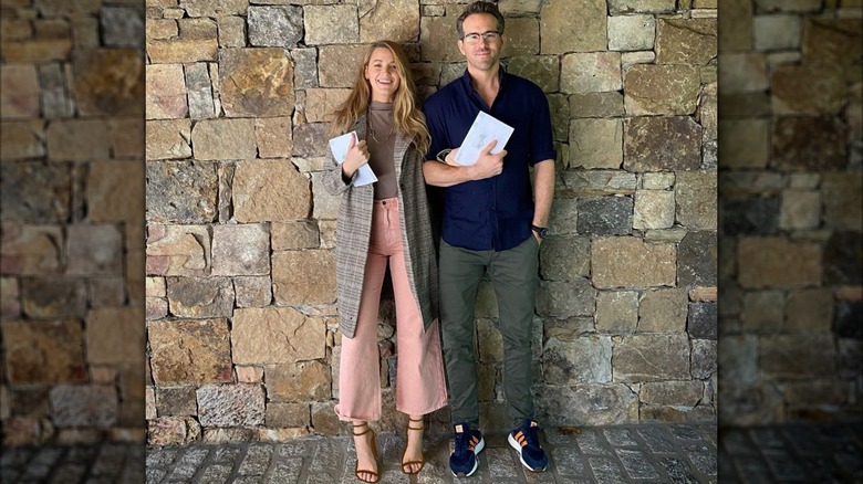 Blake Lively and Ryan Reynolds posing against a stone wall