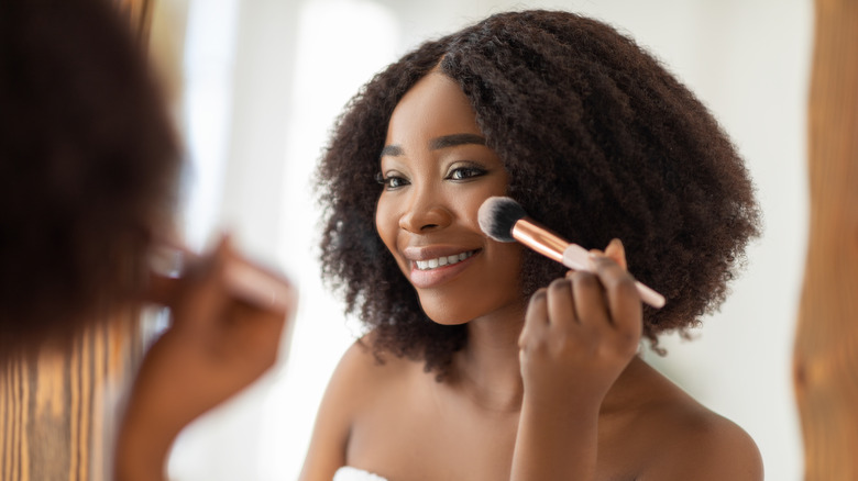 Black woman applying blush