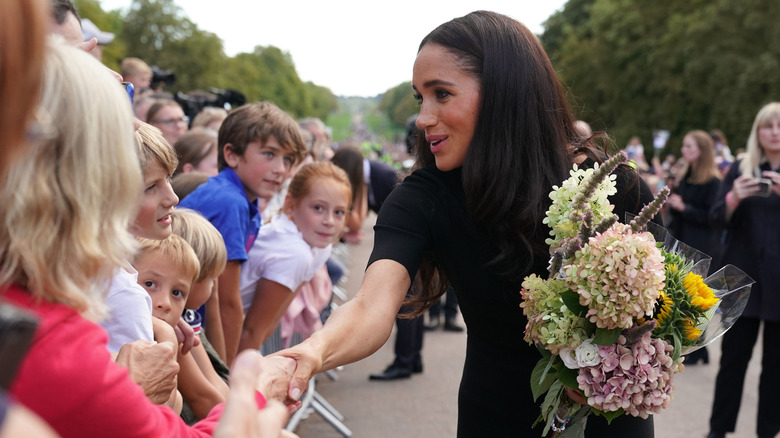 Meghan Markle greets mourners while holding flowers