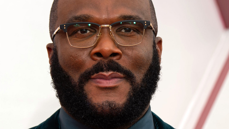 Tyler Perry slight grin with facial hair and glasses