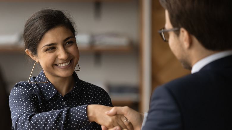 Woman smiling at a man, shaking hands