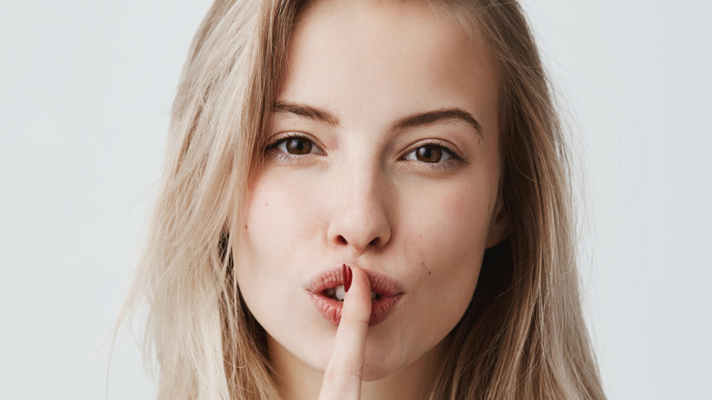 Woman holding her finger to her mouth