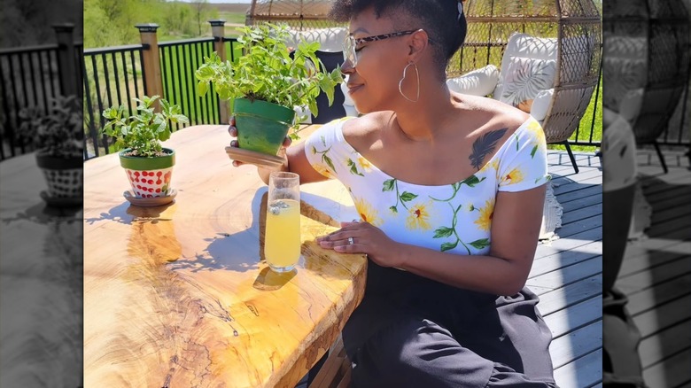 Mary Tjon Joe Pin smelling a plant in a garden table