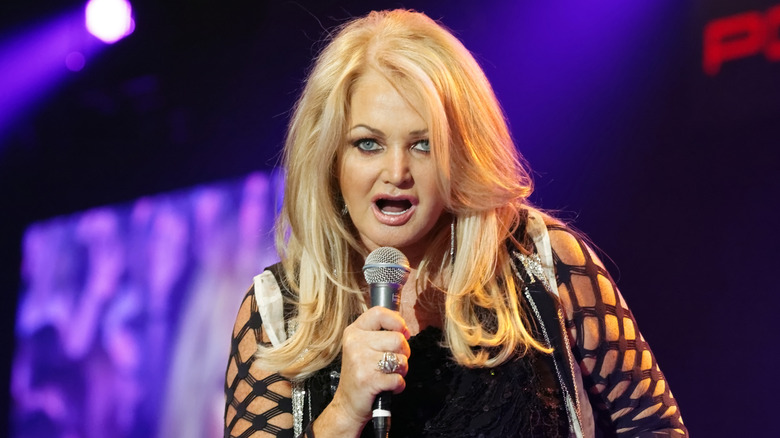 Bonnie Tyler performing onstage in 2019 in a black cutout sleeve dress