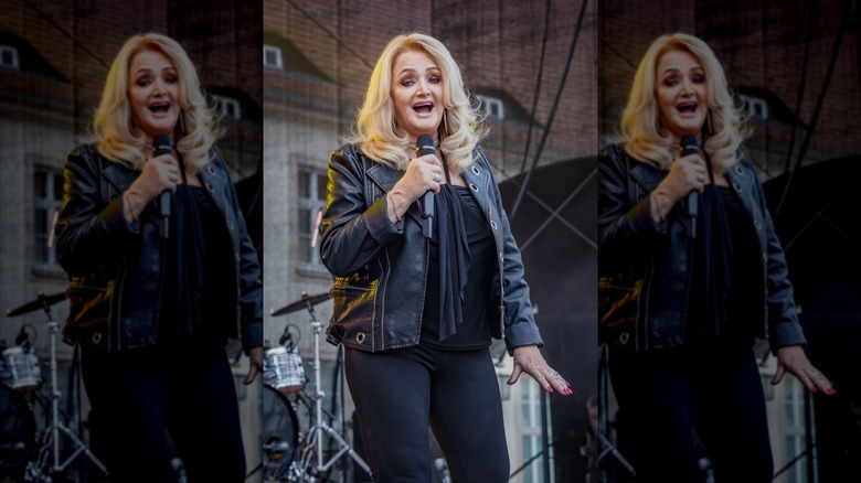 Bonnie Tyler on stage holding a microphone wearing all black