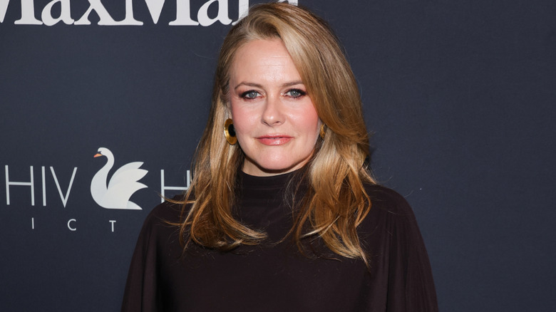 Alicia Silverstone posing in black outfit against Max Mara background