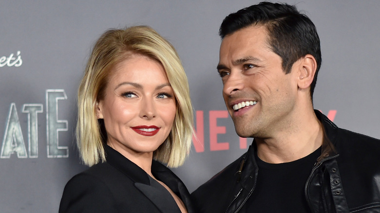 Kelly Ripa and Mark Consuelos smiling together and posing.