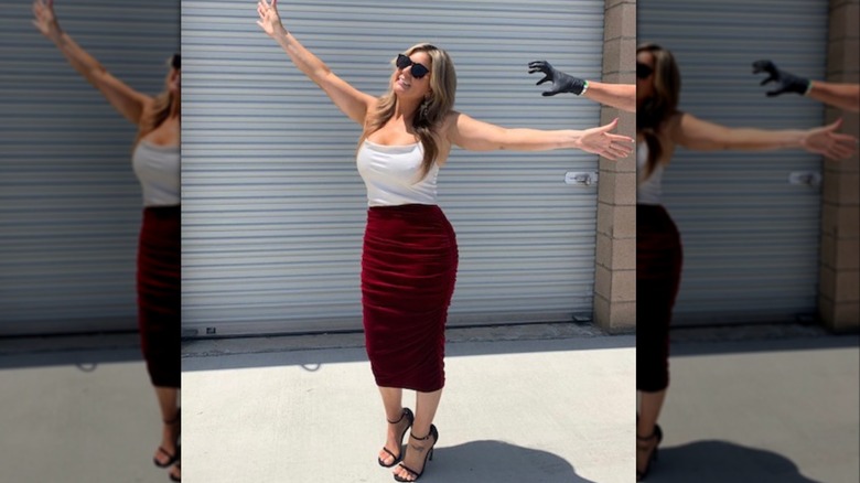 Brandi Passante stands in front of a storage unit in a red and white dress with arms outstretched
