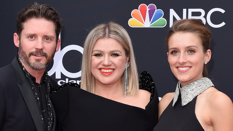 Savannah Blackstock smiling next to Brandon Blackstock and Kelly Clarkson at the Billboard music awards.