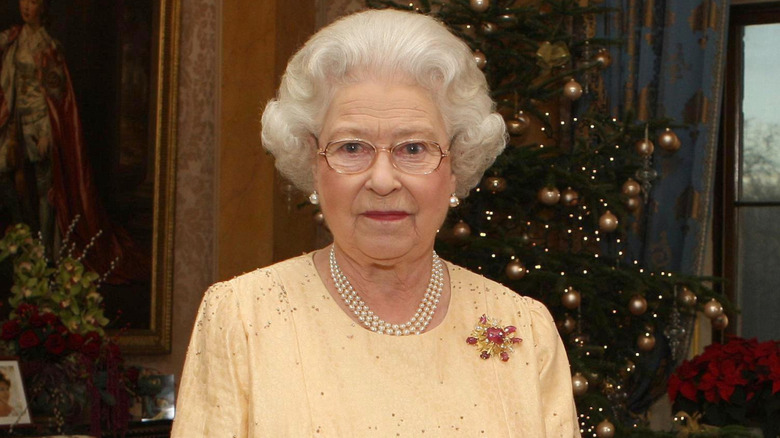Queen Elizabeth II presenting with a stiff upper lip in front of a Christmas tree