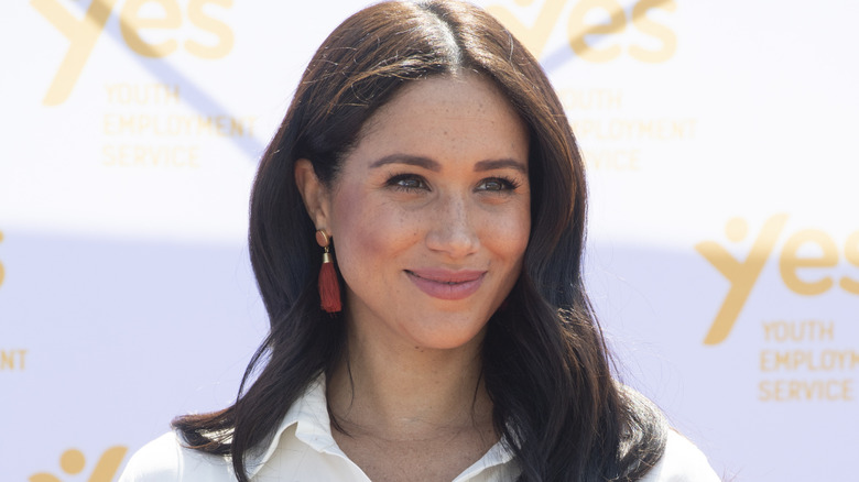 Meghan Markle stands in the sunshine and smiles for a photo