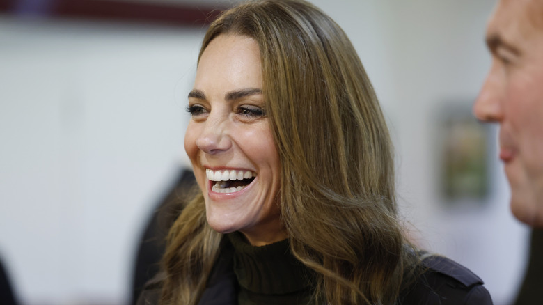Kate Middleton smiles and laughs as she talks with a group of people